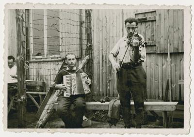 Two Belgian POWs play music outside a barrack in Stalag 10
